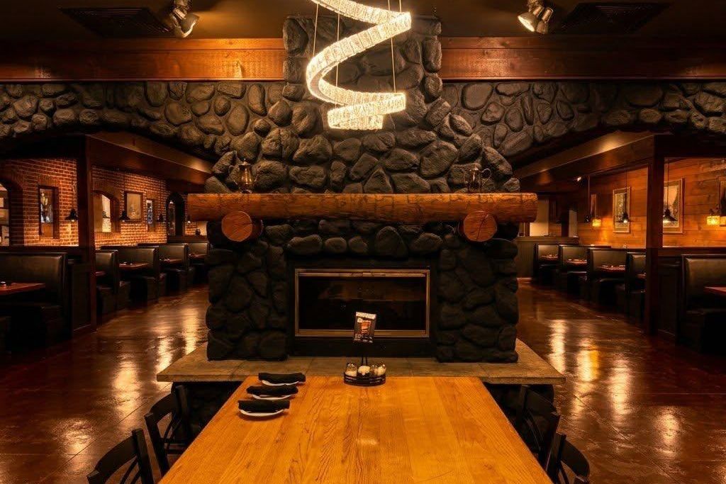 The Gusto Italian dining room — stone fireplace, booths and a long communal table